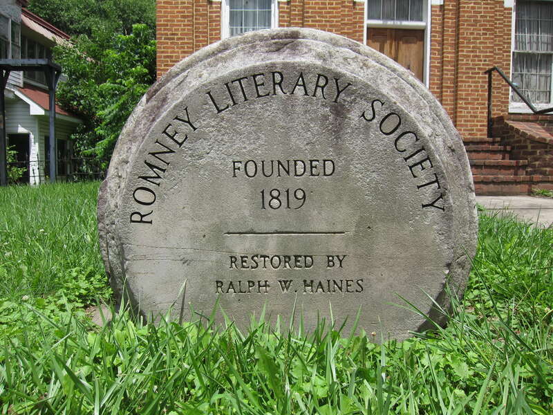 A historical marker commemorating the Romney Literary Society and the restoration of Literary Hall. Literary Hall (1870) is a 19th century brick edifice located at the corner of Main (U.S. Route 50) and High (West Virginia Route 28) Streets in Romney