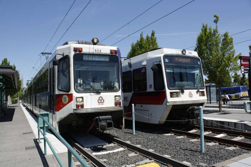 TriMet MAX trains at Beaverton Transit Center in Beaverton, Oregon, USA.  A Blue Line train departing for Hillsboro is on the left, and a Red Line train waiting to depart for Portland International Airport is on the right.