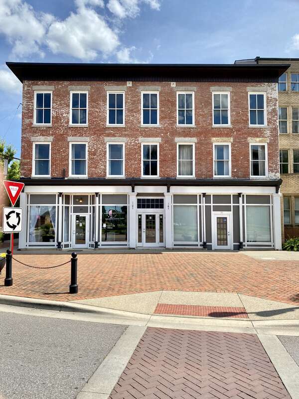 Built in the 1853 and modified in 1866, this Italianate-style three-story seven-bay building features a red brick facade with the remnants of white paint still visible on the exterior, a cornice that has lost its ornamentation, two-over-two and