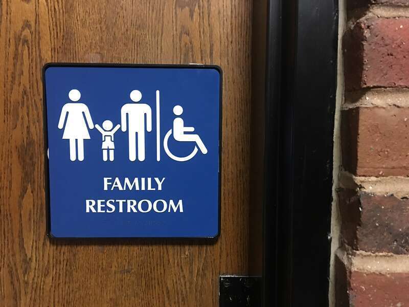 A sign indicating a gender-inclusive, children &amp;amp; family, ADA compliant restroom at a public library in Nashua, New Hampshire