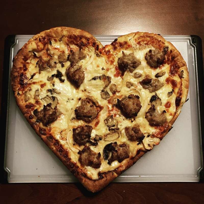 A heart-shaped pizza from Rocky Rococo, topped with sausage, mushrooms, and onions.  Heart-shaped pizzas are their specialty pizza for St. Valentine’s Day.