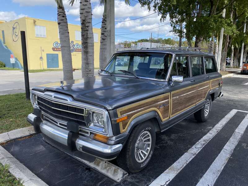 Jeep Grand Wagoneer (SJ) - the original luxury SUV - finished in gray with standard wood-grain side panels. Photographed in Coral Gables, Florida.