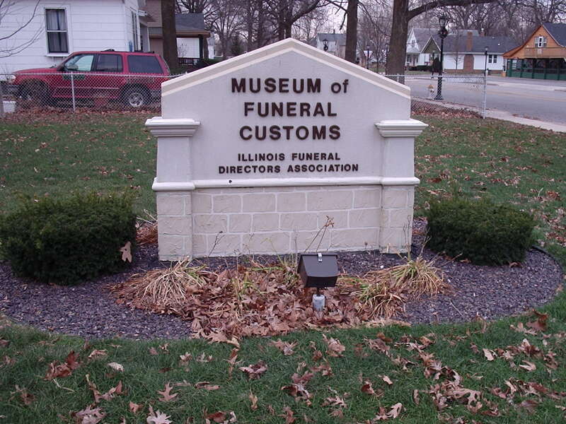 Outside sign at the Museum of Funeral Customs, Springfield, Illinois.  Fallen oak leaves collect on the ground.