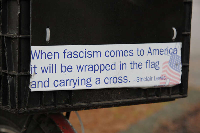 Closeup of bumper sticker with famous Sinclair Lewis line &quot;When fascism comes to America it will be wrapped in the flag and carrying a cross&quot;

This quote is often attributed to Sinclair Lewis but has not been verified. The Sinclair Lewis Society