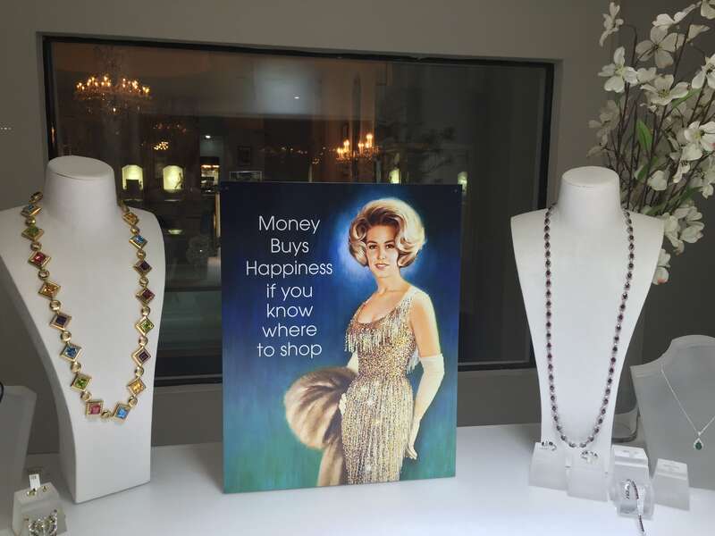 Jewelry store window display on Worth Avenue in Palm Beach, Florida, with a sign: &quot;Money buys happiness if you know where to shop&quot;