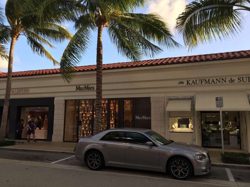 Worth Avenue in Palm Beach, Florida, with a silver Chrysler 300. A Max Mara outlet is also visible.