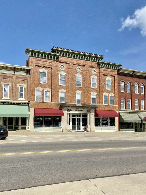 Built around the turn of the 20th Century, this Renaissance Revival-style building features an orange brick facade, divided into five bays by pilasters with brick corbeling above the third floor windows, stone window headers, a heavily bracketed