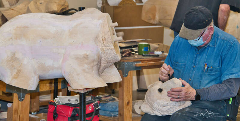 A veteran carver working on a bear head with its body on the table next to him. I was so lucky to be allowed behind the ropes access to the carvers to take photos.