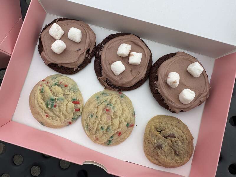 Three types of cookies from Crumbl Cookies in Petaluma, California: Frozen hot chocolate (chocolate cookie with hot cocoa-flavored mousse and mini marshmallows), holiday confetti (warm vanilla sugar cookie with red and green sprinkles) and chocolate