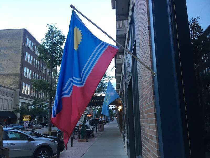 A flag of Sioux Falls, flying in Downtown Sioux Falls, with a flag of South Dakota in the background.