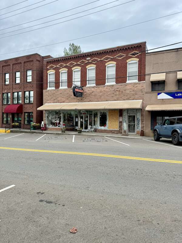 Built in 1919, this two-story commercial building features a red brick exterior, one-over-one windows in arched bays on the second floor, buff brick trim, a corbeled brick cornice, a pale pink brick first floor with a recessed entrance door flanked