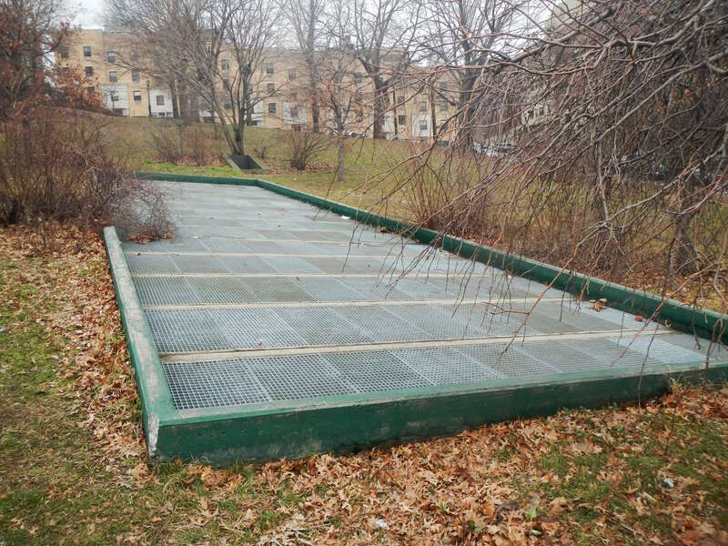 Looking north at grate, a vent for the Concourse Line, on a cloudy day.