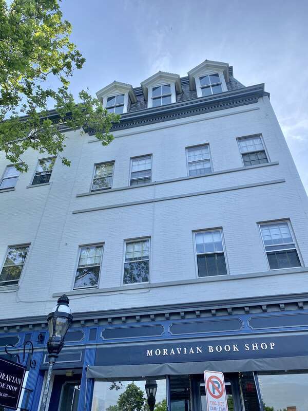 Built in the late 19th Century, these Second Empire and Renaissance Revival-style buildings feature painted brick front facades, truncated window openings with replacement windows, cornices with dentils, first floor storefronts with decorative trim