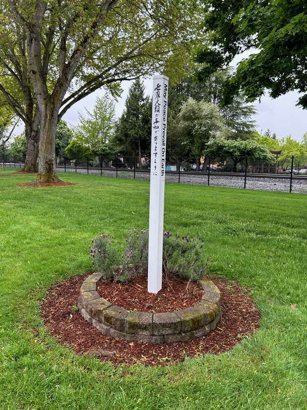 Pole that reads &quot;may peace prevail on earth&quot; in several languages at the Burlington Green-Yangzhou Park in Kent, Washington.
