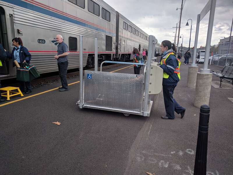 Amtrak employees wheel a portable lift to assist a passenger off the northbound Coast Starlight at Eugene station on October 2018