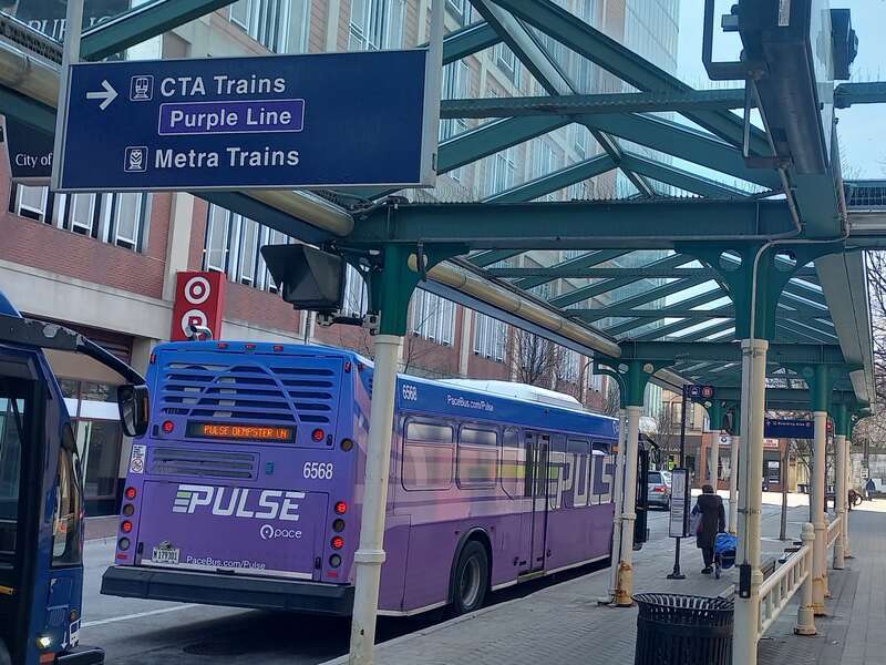 A bus on the Pulse Dempster Line stopping at Davis station (CTA) and Evanston Davis Street station (Metra) in Evanston.
