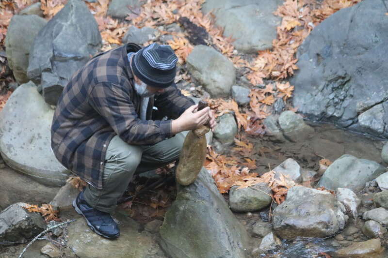 A man in a knit hat balances rocks near Swanson Creek in Uvas Canyon County Park, in Morgan Hill, California.