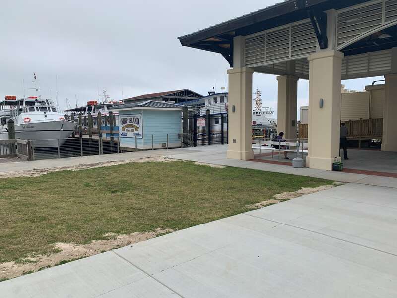 Cement building with metal benches beneath. Boats docked near a pier in the background.
Ship Island Excursions Gulfport Pier