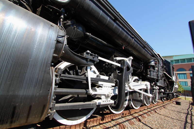Closeup of cylinders and drive shafts.  A single bar powers all five driving wheels on each side of the locomotive.