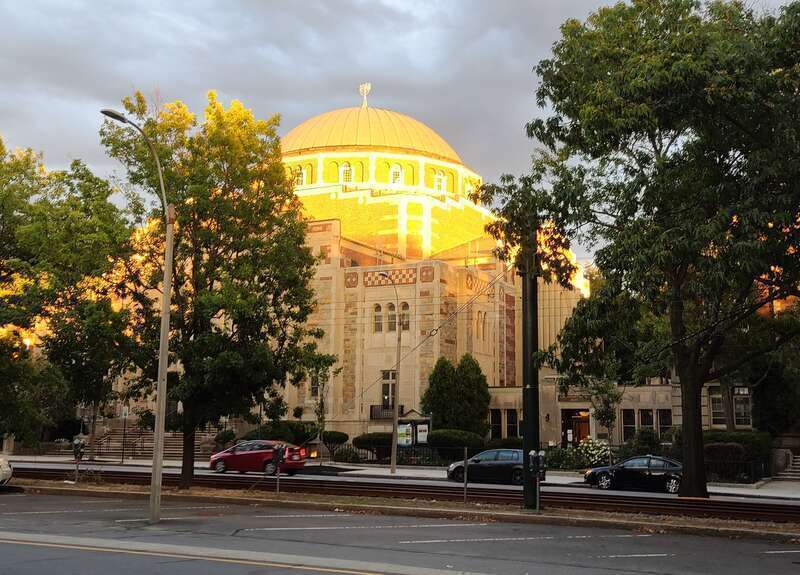 A large Jewish Temple with sunlight shining on the top of the building.