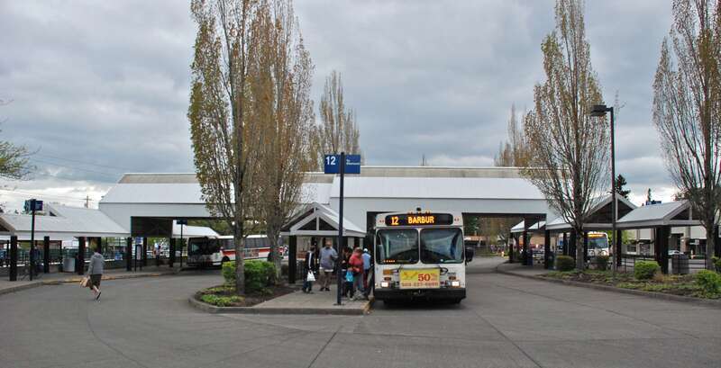 TriMet's Tigard Transit Center, in Tigard, Oregon, with buses loading or laying over in all three lanes.  In the central lane, bus 2826 (a 2005 New Flyer D40LF) is loading on line 12-Barbur Blvd, en route to Sherwood. The transit center opened for
