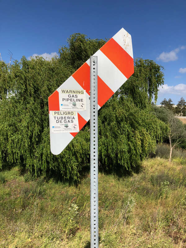 A gas pipeline marker posted by the Pacific Gas and Electric Company along the bicycle trail on the left bank of the Guadalupe River in the Ulistac Natural Area in Santa Clara, California, United States. The lower end of a paddle marker indicates the