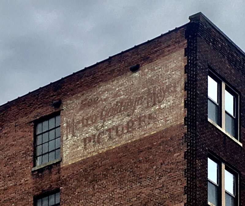 As seen in May 2020: a ghost sign on the rear of the Byers Building in the Theater District of downtown Buffalo, New York, facing West Tupper Street, urges readers to &quot;See Metro-Goldwyn-Mayer Pictures&quot;.