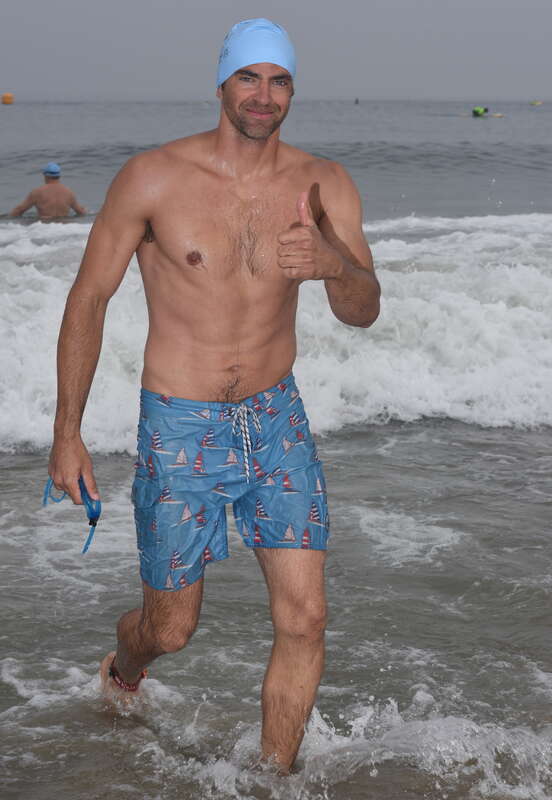 A tall athletic man exits the water wearing light blue nautical themed board shorts with a sail boat pattern after his warm-up swim.

VFJ_0215_rot1.6_cr