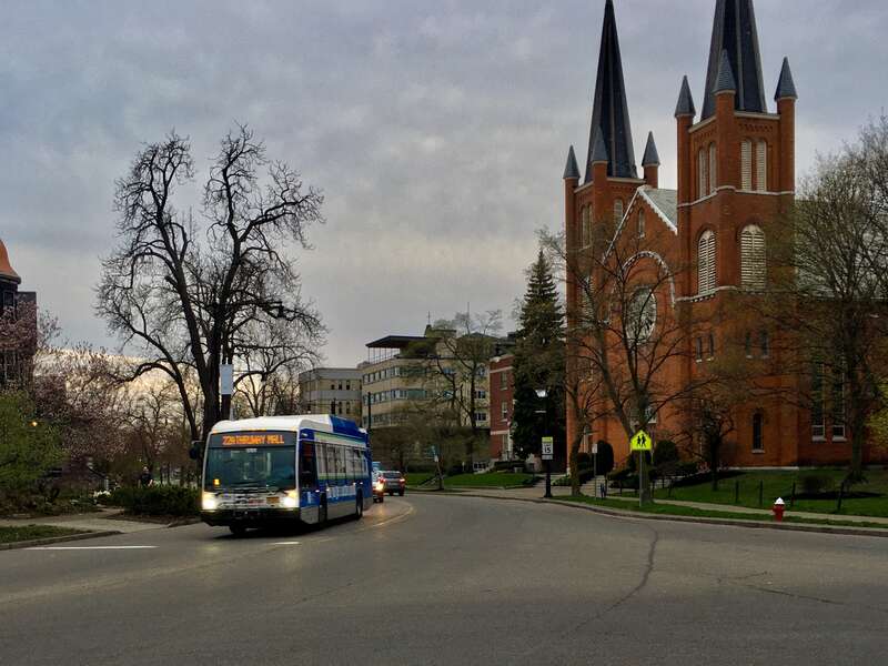 As seen on the West Side of Buffalo, New York on a balmy April 2021 evening, an NFTA Metro Bus on route 22 - immediately after having passed the former Holy Angels Catholic Church - curves eastward along Porter Avenue toward Symphony Circle. Its trip