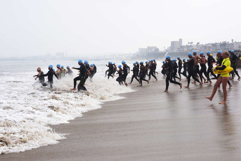 The one-mile race begins. Participants rush into the ocean.
The rules stated that no wet suits were allowed in swim events but as you can see, this entire group consists of swimmers wearing wet suits.
Swimsuit clad swimmers raced in a second wave.