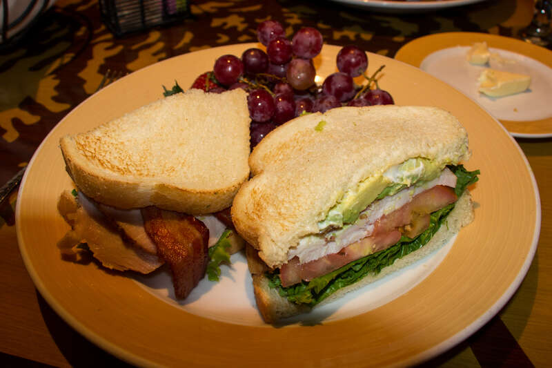 Lunch at Storytellers Cafe: Slow-roasted Turkey Clubhouse - Served on Toasted Country Bread with Bacon and fresh slices of California Avocado served with Fresh Fruit.