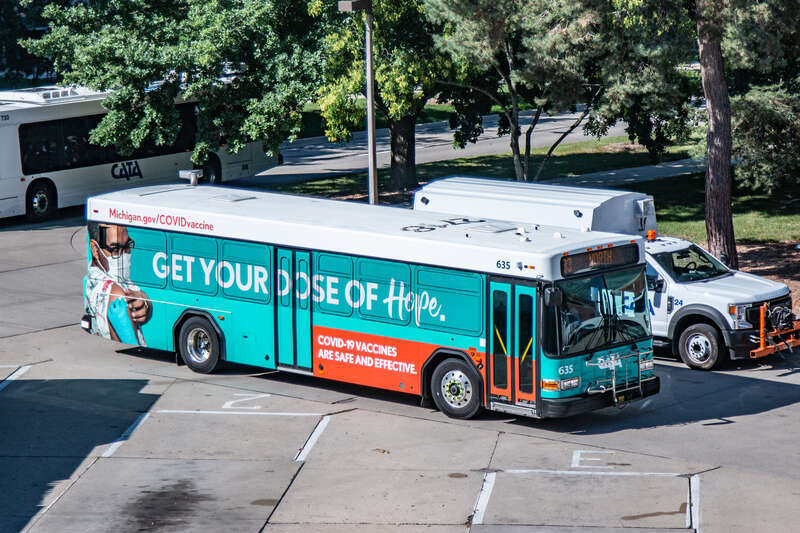 Capital Area Transportation Authority bus #635 at the CATA Transportation Center in East Lansing, Michigan in 2021. This bus is wrapped with graphics promoting COVID vaccines. The roof of the bus is still numbered 2718, the fleet number of this bus