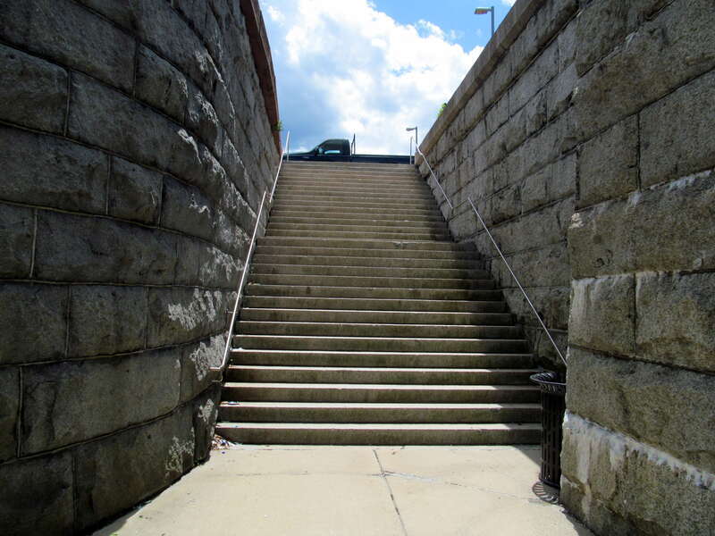 Stone staircase from Court Street in Brockton, photographed in June 2017. The staircase was built in the late 1890s as access to the newly-elevated station; it now serves as access to the modern MBTA station.