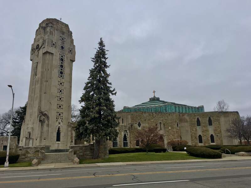 As seen in December 2020: a panoramic view of the National Shrine of the Little Flower in Royal Oak, Michigan from Twelve Mile Road just east of Woodward Avenue, comprising the Charity Crucifixion Tower (left) and the sanctuary (right).