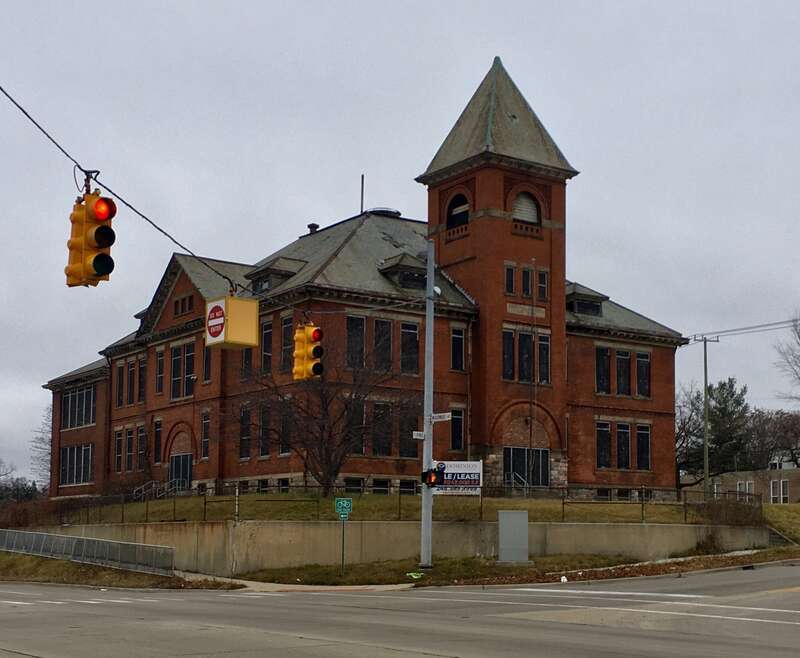 The former Central School, 101 East Pike Street at Woodward Avenue, Pontiac, Michigan, December 2020. Built in 1893 in a Richardsonian Romanesque style (note the prominent Syrian arches crowning the front and side entrances as well as featuring in