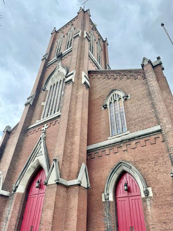 Built in 1866-1867, this Gothic Revival-style building was constructed for St. John’s German Evangelical Church, which later became the St. John United Church of Christ.  The building features a red brick exterior, stone trim, a gable roof, brick