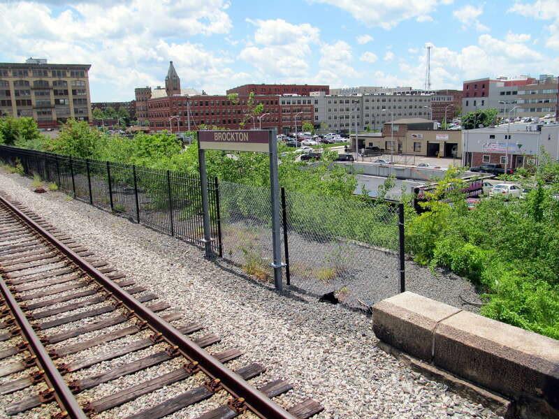 Station sign at Brockton station in June 2017, with the downtown area behind