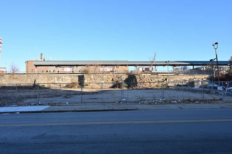 A fenced-off vacant lot in front of Brockton Station