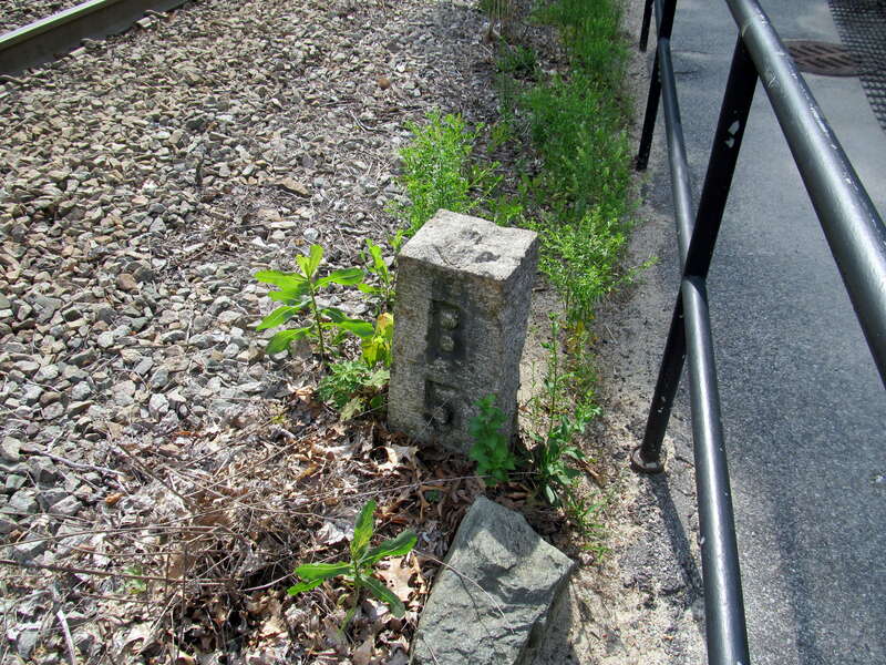 Milepost indicating 5 miles to Boston along the Highland Branch, just east of Beaconsfield station, in June 2016. The marker indicates the distance to the pre-1899 Kneeland Street terminal, not the slightly further distance to South Station.