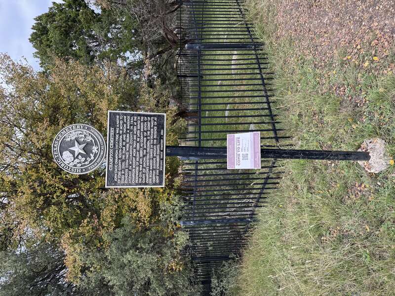The Texas Historical Commission Marker for Champion Cemetery near Texas’ Bushy Creek neighborhood. Champion Cemetery itself is present in the background.