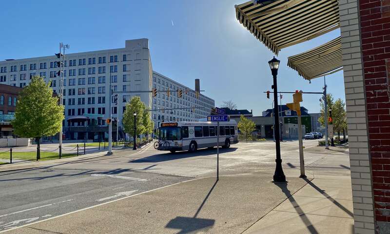 An outbound NFTA Metro Bus #15 passes eastward from Swan Street onto Seneca Street through the center of the Larkinville section of Buffalo, New York, with its warehouses redeveloped into office parks, restaurants, and loft apartments, as seen on a