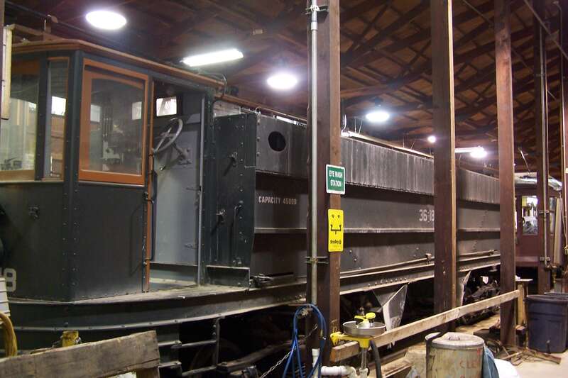 A work car under repair in the shop at the PA Trolley Museum in Washington, PA.  This car will assist in reballasting the "right of way" at the museum.