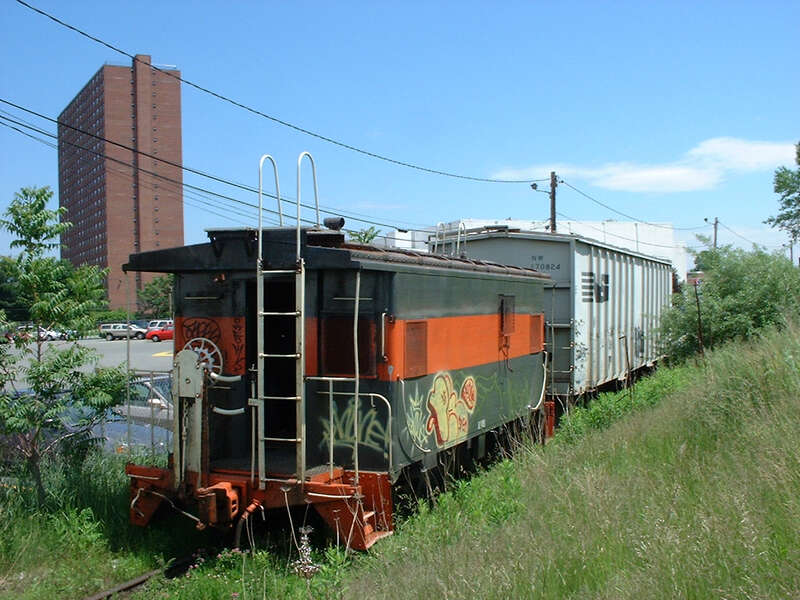 Caboose and hopper car parked on the Watertown Branch near Alewife in June 2002