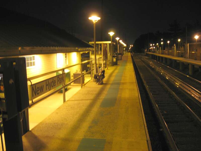 Looking east along en:New Hyde Park (LIRR station) northern platform at night as a westbound train approaches in the distance.