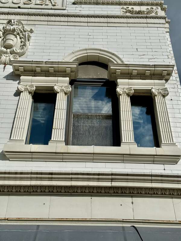 Built in 1855 and renovated to its present First Renaissance Revival-style appearance around the turn of the 20th Century when it was home to the drug store of Christian Rouser, this building is clad in painted brick with a green marble and white