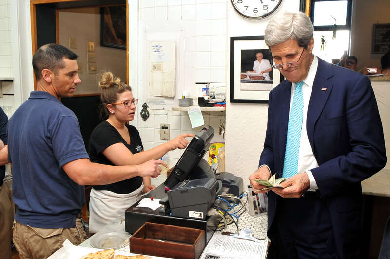 U.S. Secretary of State John Kerry pays for three takeout pizzas he bought at the famed New Haven, Connecticut, pizza shop Frank Pepe's during an impromptu stop after the 1966 Yale University graduate addressed Class Day ceremonies on May 18, 2014.