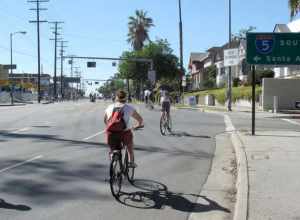 CicLAvia 2010 bicyclists heading west on Fourth Street, passing an exit ramp from Interstate 5 that has been closed with yellow tape. An entrance ramp to Interstate 5 southbound is just to the left of the image.