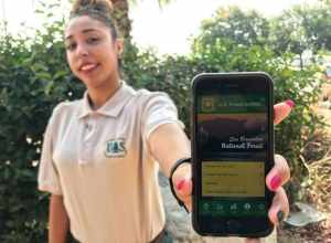 Visitor Service's Receptionist Rebecca Miller holds an iPhone displaying the landing screen for San Bernardino National Forest's first mobile app. 

(Forest Service photo by Zach Behrens)
