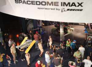 Patrons await entry to the IMAX theater at the United States Space &amp; Rocket Center.  A model of Hubble Space Telescope is suspended in the foreground.