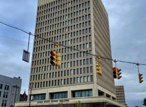 The Utica State Office Building, 207 Genesee Street at Blandina Street, as seen on an August 2021 afternoon. With a simple, angular design of regular rows and columns of narrow windows deeply recessed into a smooth-textured façade of concrete panels,